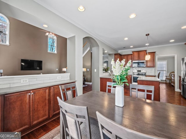 dining room featuring arched walkways, recessed lighting, crown molding, and dark wood-style flooring