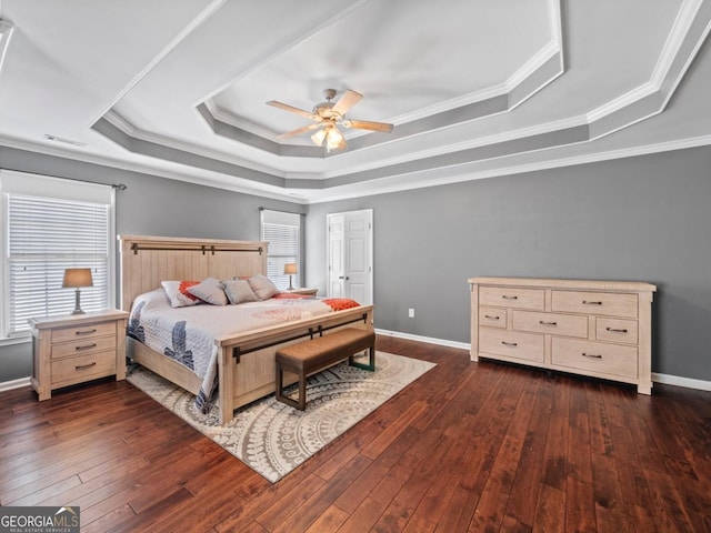 bedroom featuring a tray ceiling, multiple windows, baseboards, and dark wood-style floors