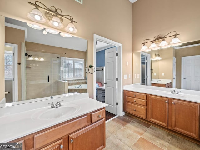 full bath featuring two vanities, a bath, a stall shower, and a sink