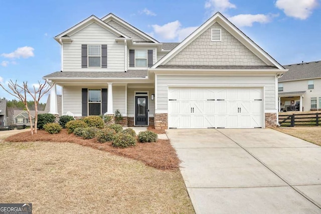 craftsman-style home with a garage, fence, stone siding, and driveway