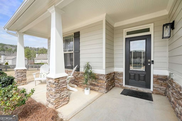 view of exterior entry featuring stone siding and a porch