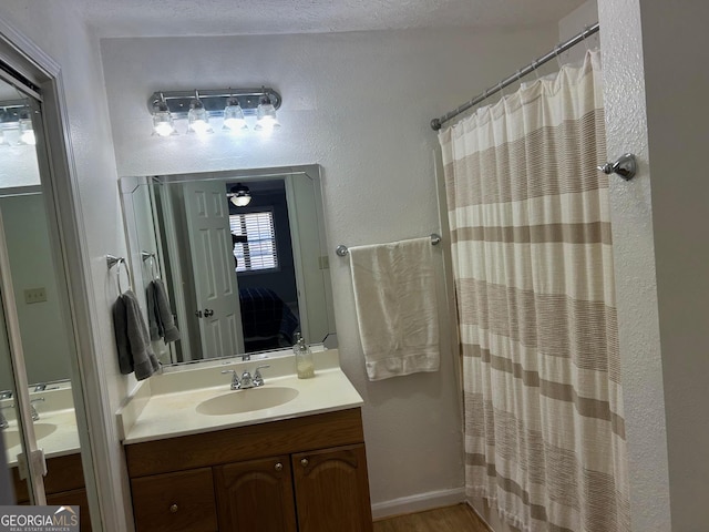 full bath featuring a shower with curtain, vanity, ensuite bathroom, and a textured wall