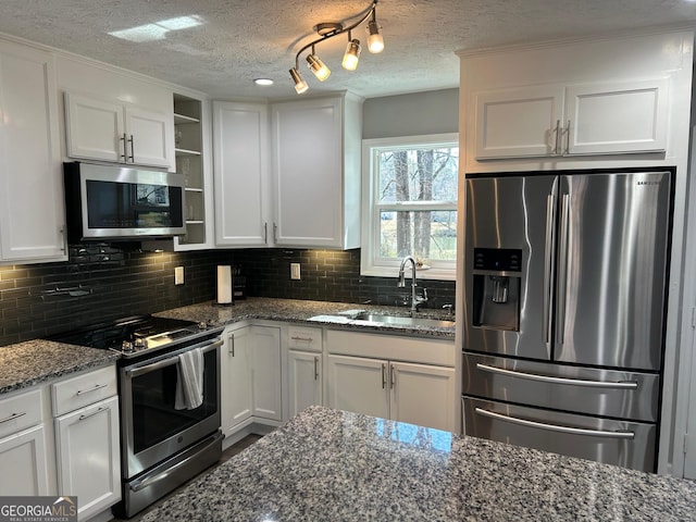 kitchen featuring a sink, backsplash, appliances with stainless steel finishes, and white cabinetry