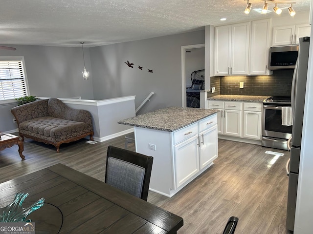 kitchen featuring backsplash, light stone countertops, appliances with stainless steel finishes, light wood-style floors, and white cabinets