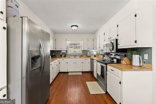 kitchen featuring dark wood-type flooring, a sink, white cabinetry, appliances with stainless steel finishes, and light countertops