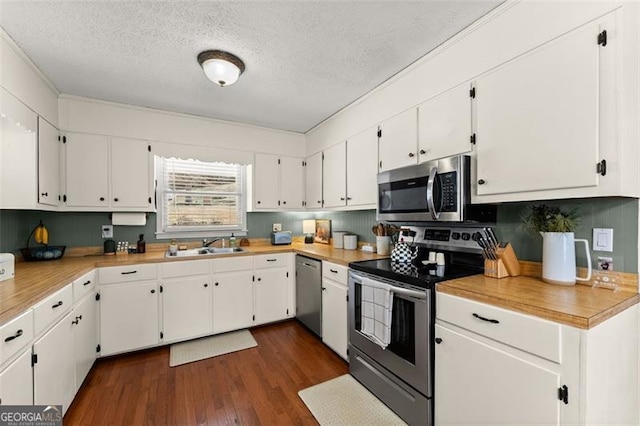 kitchen with dark wood-type flooring, stainless steel appliances, white cabinets, a textured ceiling, and a sink