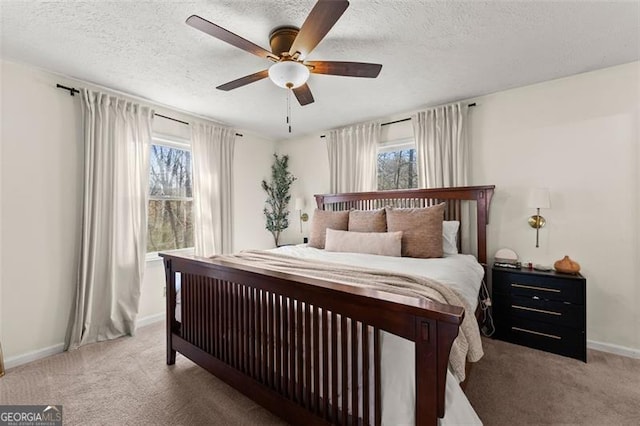 carpeted bedroom featuring ceiling fan, multiple windows, baseboards, and a textured ceiling