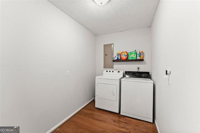 laundry room featuring a textured ceiling, wood finished floors, washing machine and dryer, baseboards, and laundry area