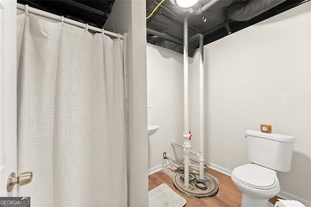 bathroom featuring curtained shower, toilet, baseboards, and wood finished floors