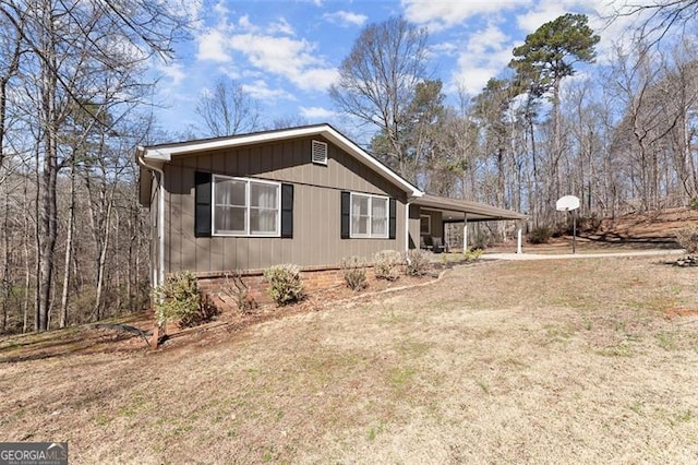 view of home's exterior featuring a carport, dirt driveway, and a lawn