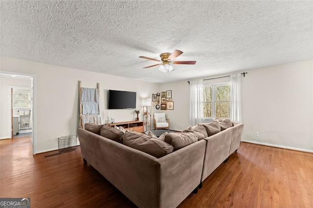 living room featuring a textured ceiling, baseboards, a ceiling fan, and wood finished floors