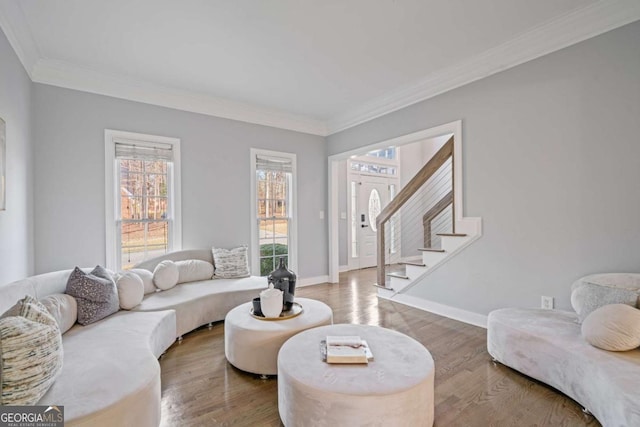 living room featuring stairs, baseboards, wood finished floors, and crown molding