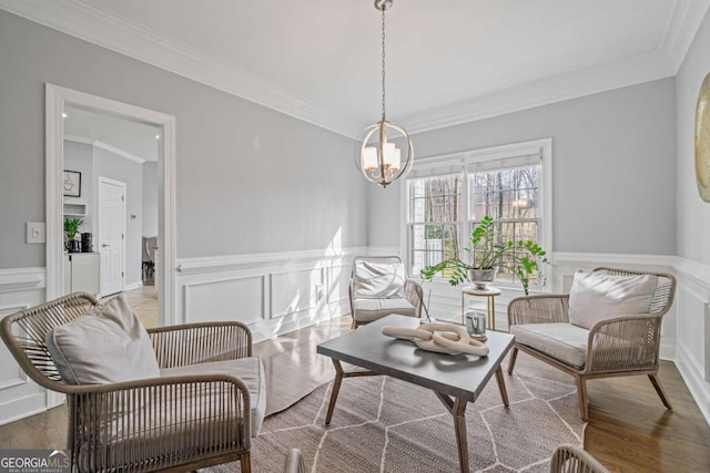 living area featuring an inviting chandelier, crown molding, and wood finished floors