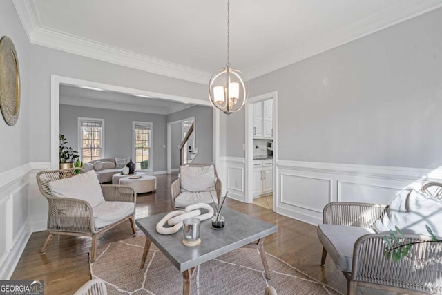 sitting room with a wainscoted wall, crown molding, a notable chandelier, and light wood-type flooring