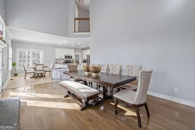 dining room with recessed lighting, baseboards, a towering ceiling, and light wood finished floors