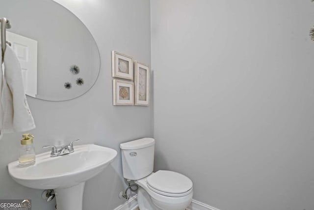 bathroom featuring a sink, baseboards, and toilet