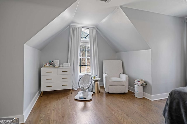 interior space with vaulted ceiling, baseboards, and wood finished floors