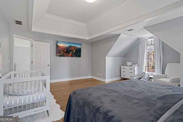 bedroom with visible vents, baseboards, wood finished floors, and crown molding