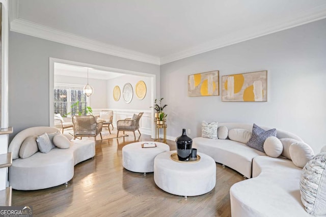 living room with a notable chandelier, crown molding, baseboards, and wood finished floors