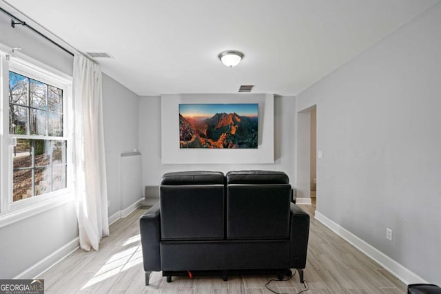 home theater room with light wood-style flooring, baseboards, and visible vents