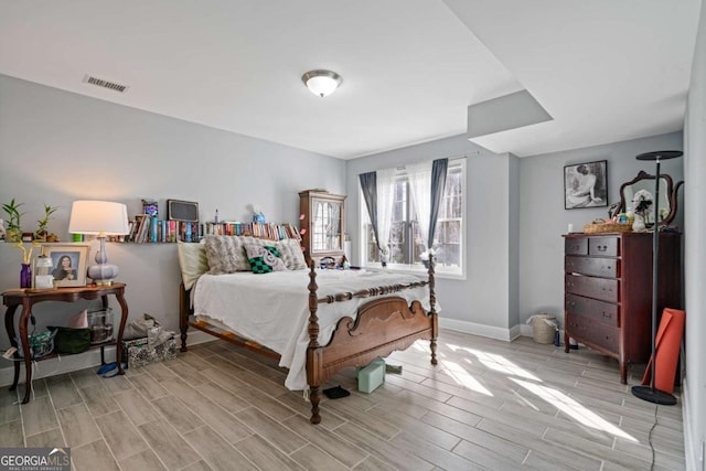 bedroom with visible vents, baseboards, and wood finish floors