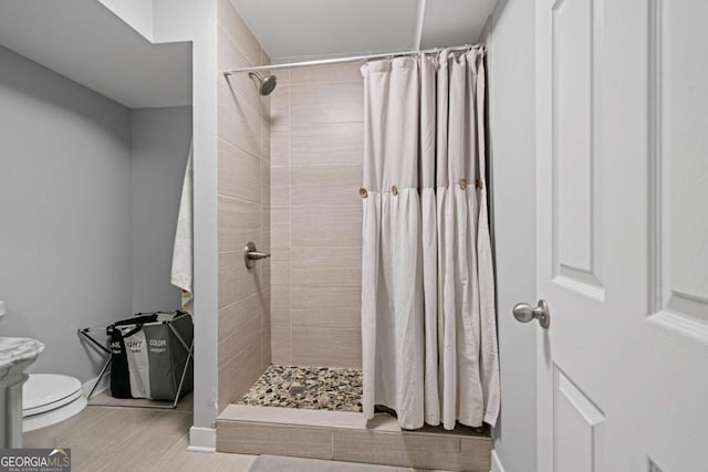 bathroom featuring a tile shower, tile patterned floors, toilet, and baseboards