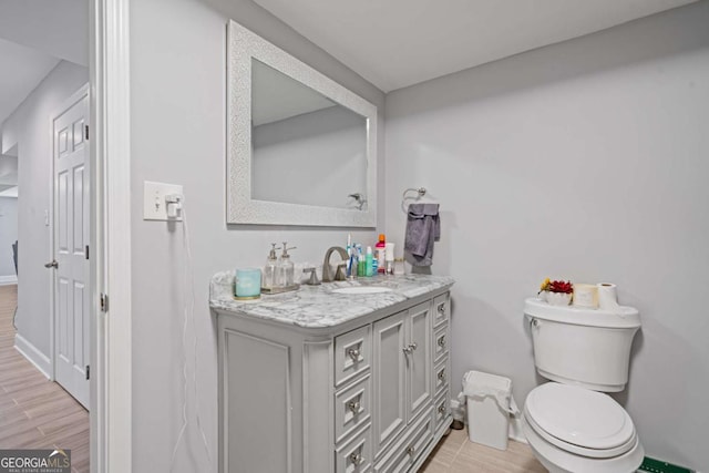 half bathroom with toilet, vanity, baseboards, and wood finished floors