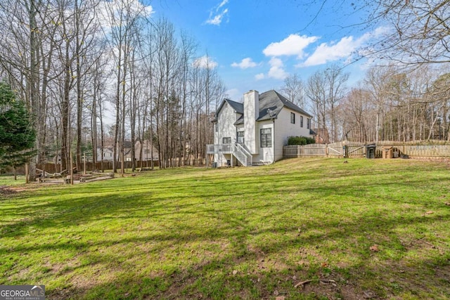 view of property exterior featuring a gate, a lawn, a chimney, and fence