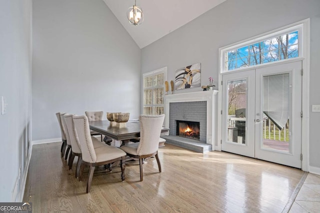 dining room featuring french doors, baseboards, high vaulted ceiling, and wood finished floors