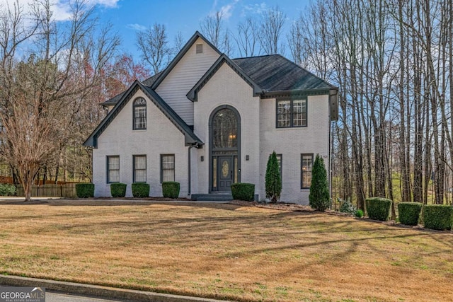 french country style house with a front yard and brick siding