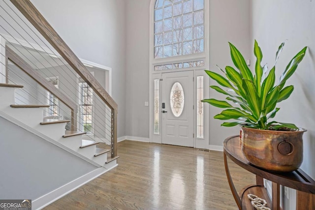 entrance foyer featuring baseboards, stairs, a towering ceiling, and wood finished floors