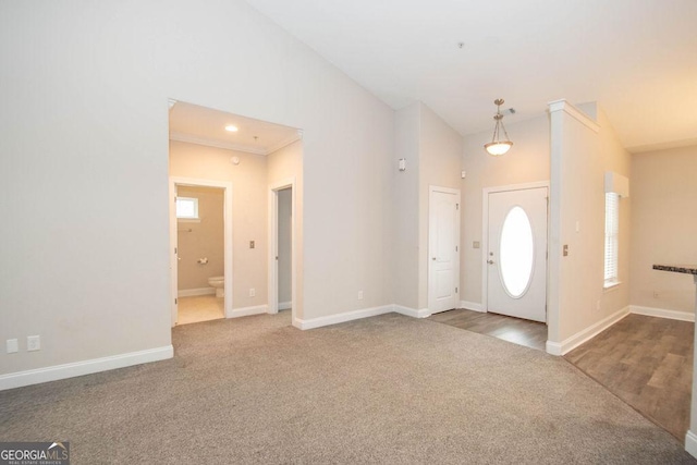 carpeted foyer featuring baseboards, a wealth of natural light, and high vaulted ceiling