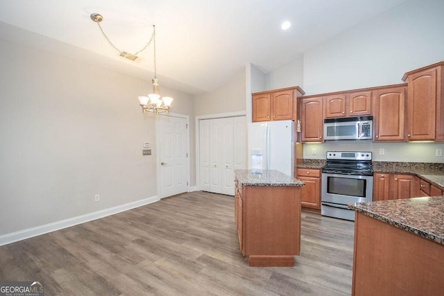 kitchen with a center island, baseboards, pendant lighting, dark stone counters, and appliances with stainless steel finishes