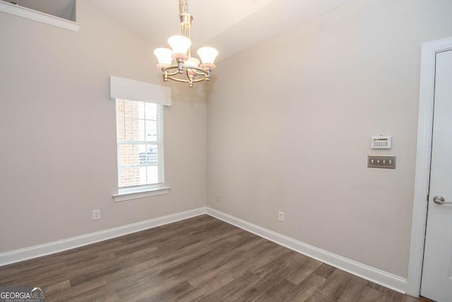 empty room featuring dark wood-style floors, an inviting chandelier, and baseboards