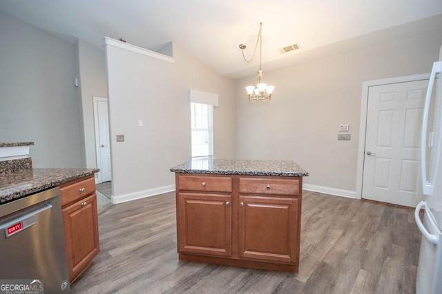 kitchen featuring brown cabinets, wood finished floors, dark stone counters, dishwasher, and vaulted ceiling