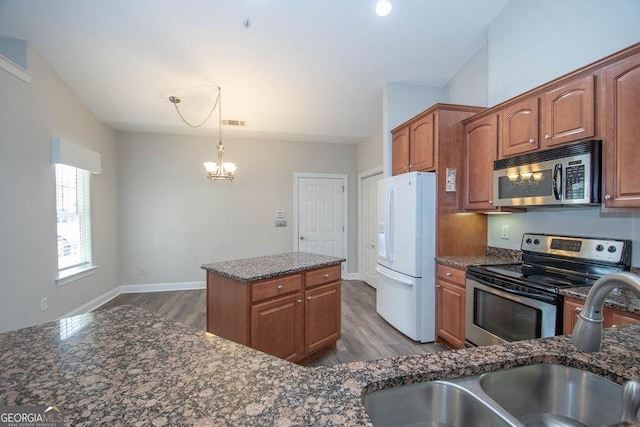 kitchen featuring a sink, dark stone counters, brown cabinets, and appliances with stainless steel finishes