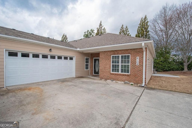 ranch-style home with an attached garage, brick siding, driveway, and roof with shingles