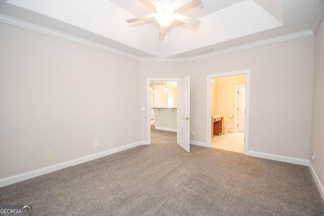 unfurnished bedroom featuring baseboards, ornamental molding, ensuite bathroom, a raised ceiling, and carpet flooring