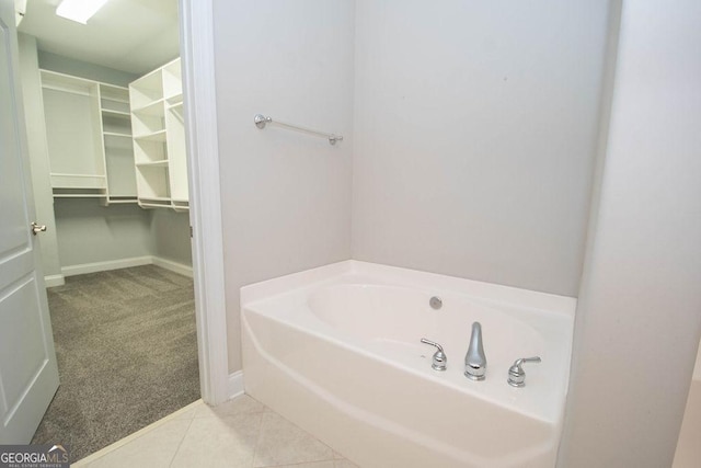 bathroom featuring tile patterned flooring, a bath, and baseboards