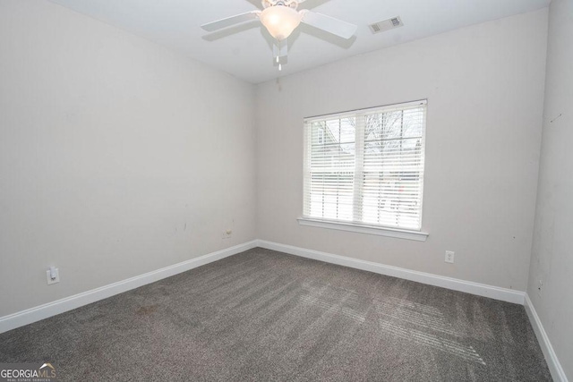 spare room featuring baseboards, visible vents, dark carpet, and ceiling fan