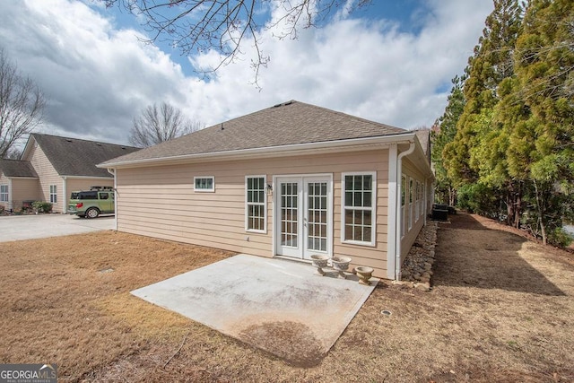 rear view of property with a patio area, french doors, and a shingled roof