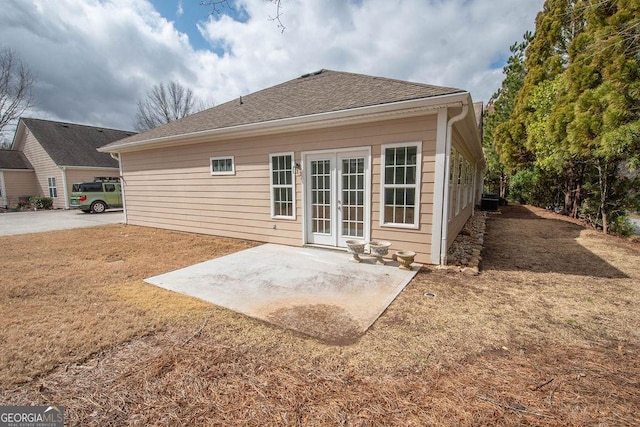 rear view of house featuring french doors, a shingled roof, and a patio area