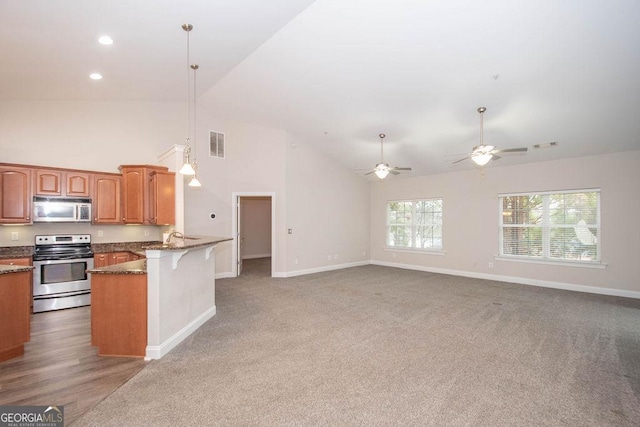 kitchen featuring visible vents, a breakfast bar, dark stone countertops, a peninsula, and stainless steel appliances