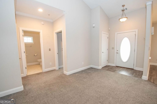 carpeted entrance foyer with baseboards and ornamental molding