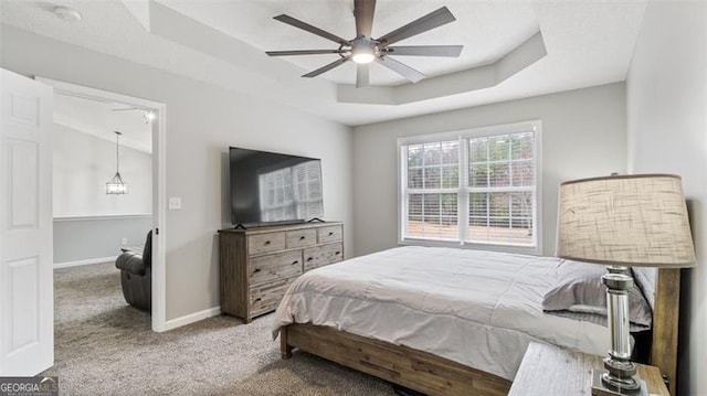 bedroom featuring baseboards, a raised ceiling, carpet floors, and ceiling fan