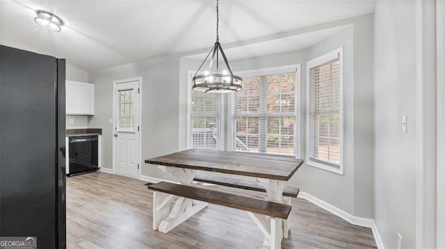 dining area featuring light wood-type flooring, baseboards, and a notable chandelier