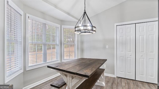 dining space with baseboards, an inviting chandelier, wood finished floors, and vaulted ceiling