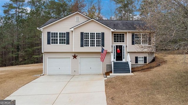 split foyer home with an attached garage, concrete driveway, and a front yard