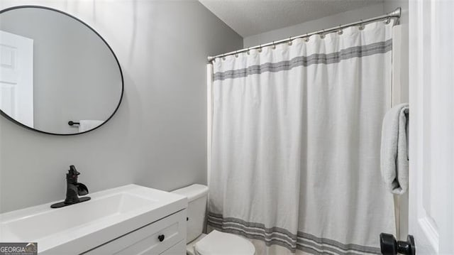 bathroom featuring toilet, curtained shower, a textured ceiling, and vanity