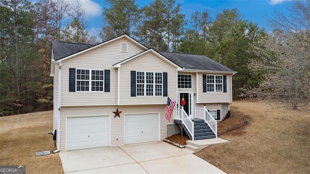 raised ranch featuring concrete driveway and a garage